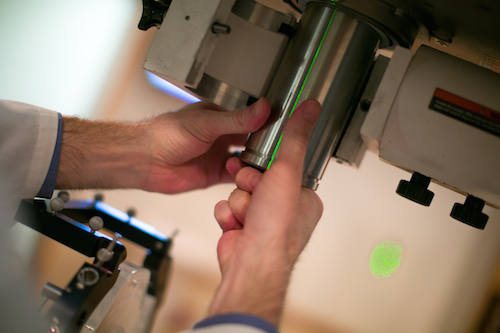 Former DHO professor, Edward Bender, inserting a cone collimator into the old radiosurgery floor stand.