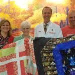 Janet Nanni, Denise Wright, Dr. Paul Harari and Peter Nanni display a couple of quilts donated to UW Radiation Oncology Clinic