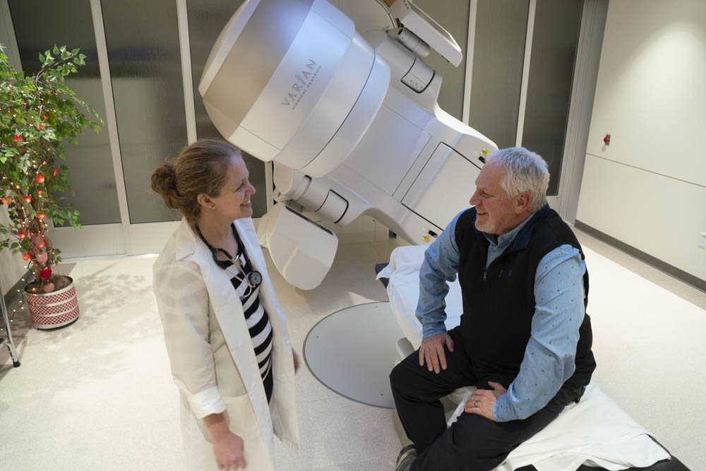 Dr. Jessica Schuster and patient Brad Glassel in front of the Varian TrueBeam Radiotherapy System at UW Cancer Clinic Johnson Creek