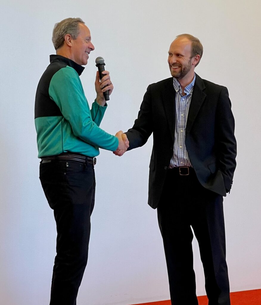 DHO Department Chairman shakes hands with Dr. John Floberg, DHO Assistant Professor, on winning Shark Tank Competition at 2021 DHO Research Retreat