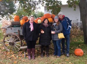 Residents in front of wagon filled with pumkins at a pumpkin patch