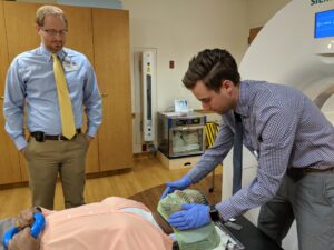 Andrew Shepard applying RT mask while a medical resident watches.