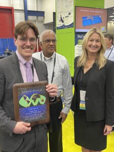 Photo of three people with award